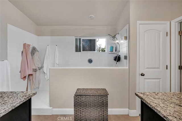 bathroom featuring tile patterned flooring, a tile shower, and vanity