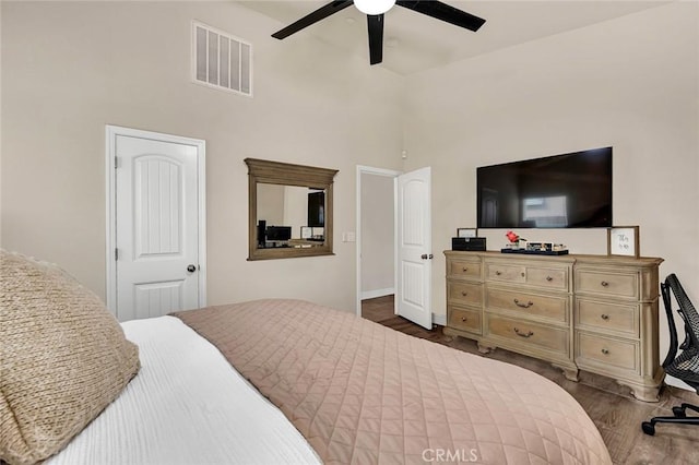 bedroom featuring dark hardwood / wood-style floors, ceiling fan, and a high ceiling