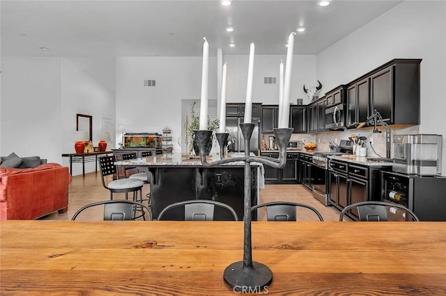 kitchen featuring a center island, a kitchen breakfast bar, tasteful backsplash, light stone counters, and stainless steel appliances