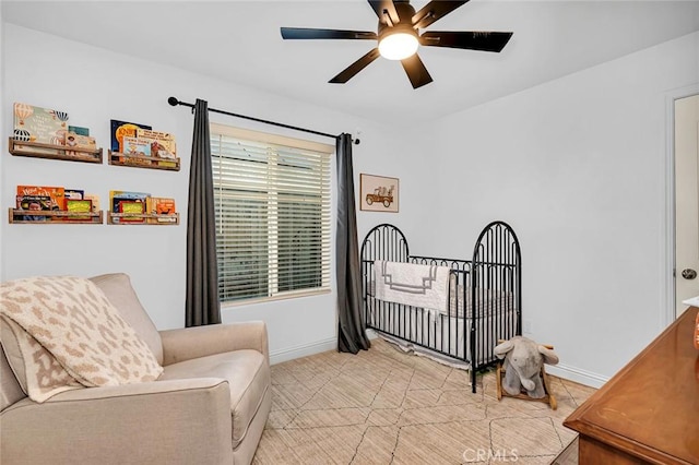 bedroom featuring ceiling fan and a nursery area