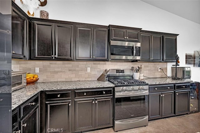 kitchen featuring decorative backsplash, stainless steel appliances, vaulted ceiling, and light stone countertops