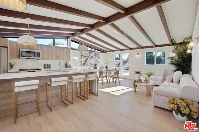 living room with light wood-type flooring, lofted ceiling with beams, plenty of natural light, and sink