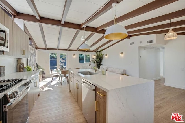 kitchen featuring sink, lofted ceiling with beams, a spacious island, decorative light fixtures, and appliances with stainless steel finishes