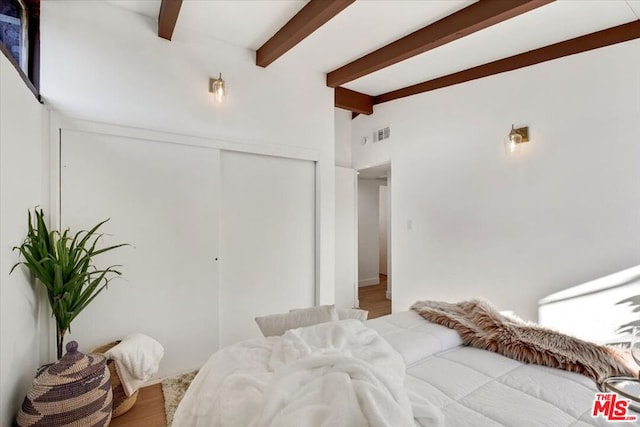 bedroom with beam ceiling and a closet