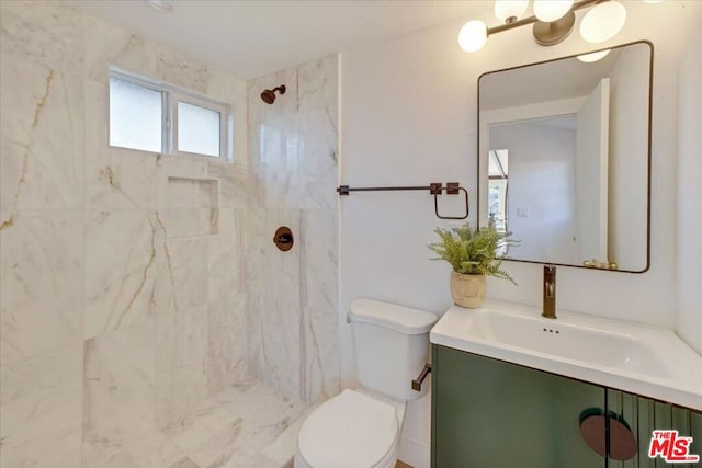 bathroom with tiled shower, vanity, and toilet