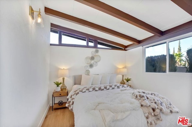 bedroom with vaulted ceiling with beams and light hardwood / wood-style floors