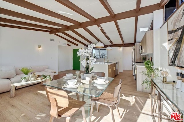 dining room featuring lofted ceiling with beams, light hardwood / wood-style floors, and sink