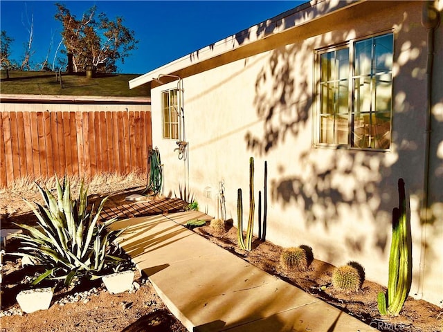 view of home's exterior with fence and stucco siding