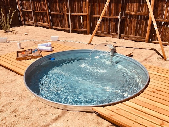 view of swimming pool featuring a jacuzzi, fence, and a wooden deck