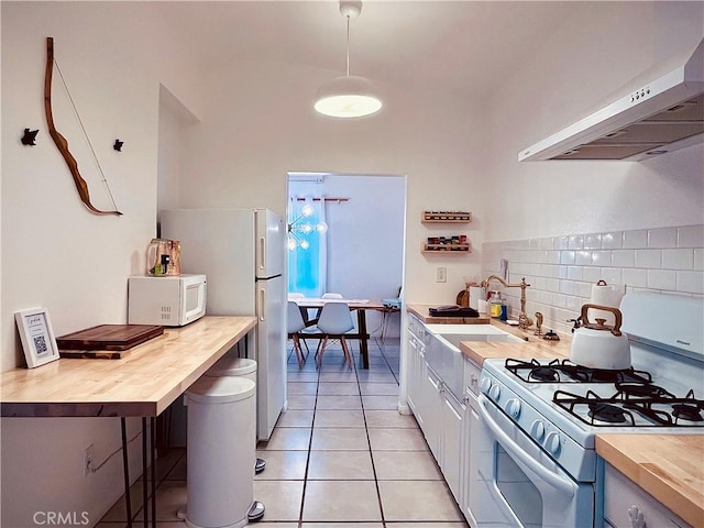 kitchen with white appliances, light tile patterned floors, butcher block countertops, range hood, and backsplash