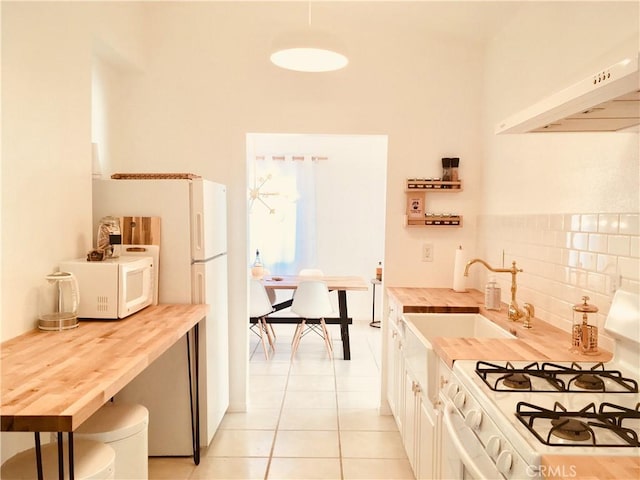 kitchen featuring white appliances, tasteful backsplash, light tile patterned floors, wood counters, and white cabinetry