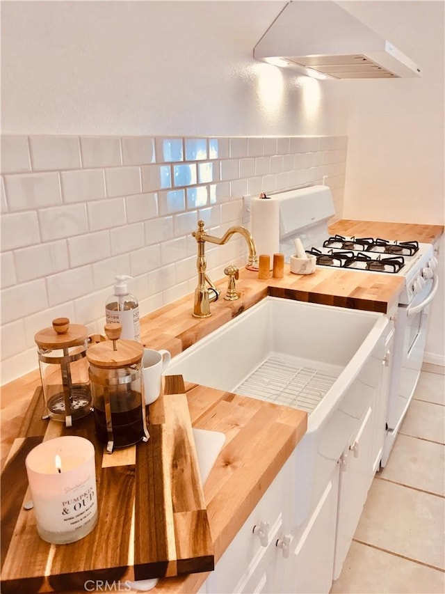 kitchen with white cabinetry, range hood, butcher block countertops, and white range with gas cooktop