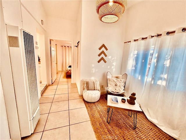 hallway with a high ceiling, a heating unit, and light tile patterned flooring