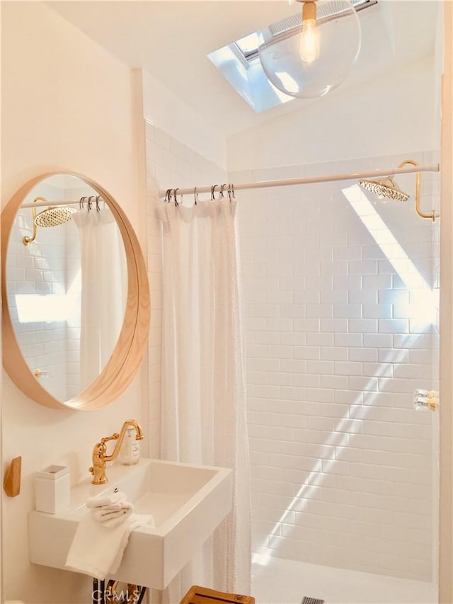 bathroom with vaulted ceiling with skylight, a sink, and a shower stall