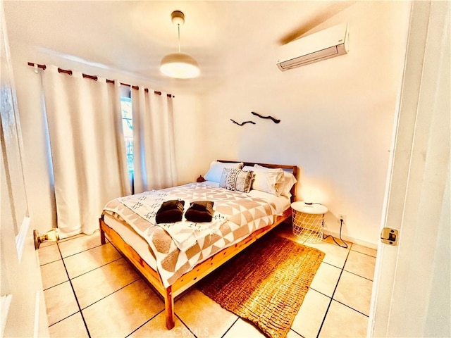 bedroom with a wall mounted air conditioner, light tile patterned flooring, and baseboards