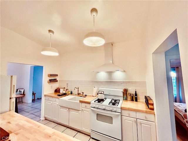 kitchen featuring light tile patterned floors, white appliances, a sink, wood counters, and wall chimney range hood