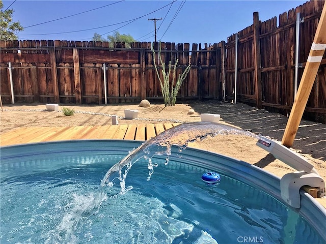 view of swimming pool with fence and a hot tub