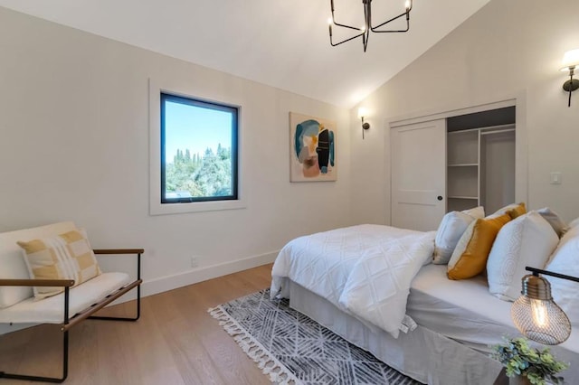 bedroom featuring an inviting chandelier, lofted ceiling, a closet, and light hardwood / wood-style flooring