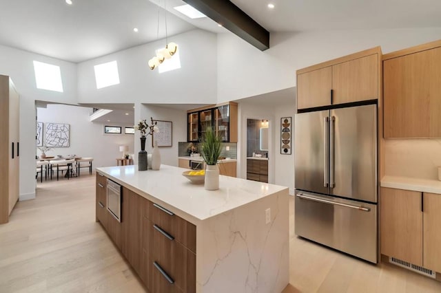 kitchen with high vaulted ceiling, beamed ceiling, light stone counters, stainless steel appliances, and a spacious island