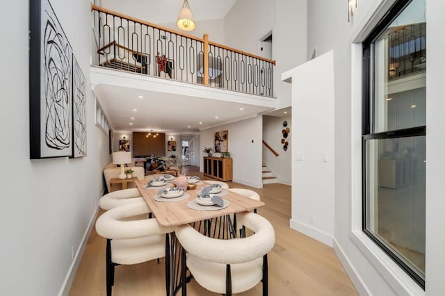 dining room with light hardwood / wood-style floors and a high ceiling