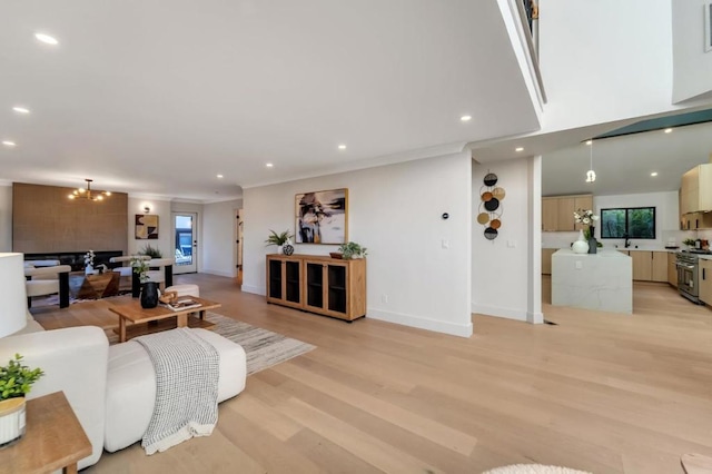 living room featuring ornamental molding, a chandelier, and light hardwood / wood-style flooring