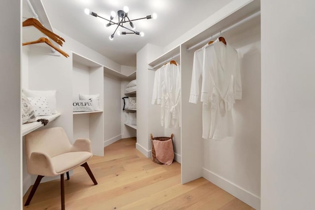 spacious closet with a chandelier and light hardwood / wood-style flooring