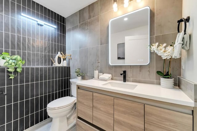 bathroom featuring vanity, tile walls, and toilet