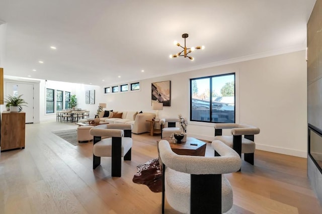 living room with crown molding, a healthy amount of sunlight, an inviting chandelier, and light hardwood / wood-style floors