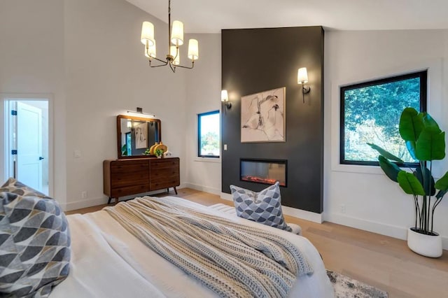 bedroom with an inviting chandelier, vaulted ceiling, and light hardwood / wood-style floors