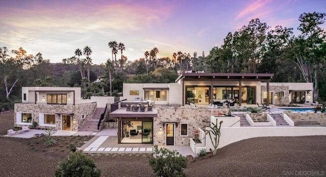 back house at dusk featuring a patio