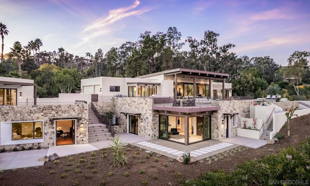 back house at dusk featuring a patio