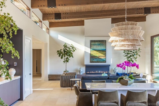 tiled dining area with beamed ceiling, a notable chandelier, wood ceiling, and a high ceiling