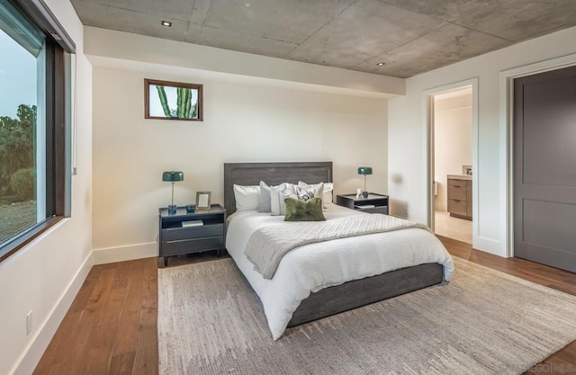 bedroom with hardwood / wood-style flooring and ensuite bath