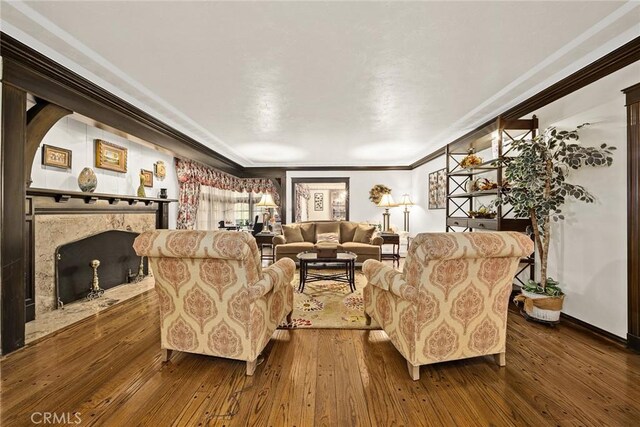 living room with hardwood / wood-style flooring, ornamental molding, and a premium fireplace