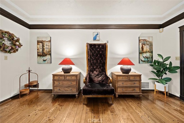 sitting room with wood-type flooring and crown molding