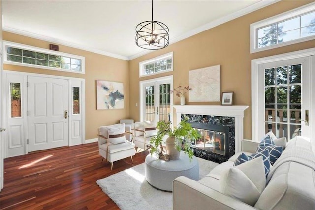 living room featuring a fireplace, a notable chandelier, a wealth of natural light, dark hardwood / wood-style floors, and crown molding