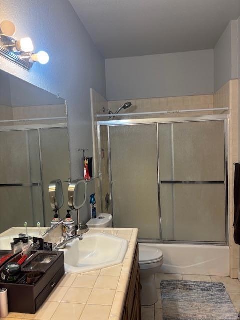 full bathroom with shower / bath combination with glass door, vanity, toilet, and tile patterned flooring