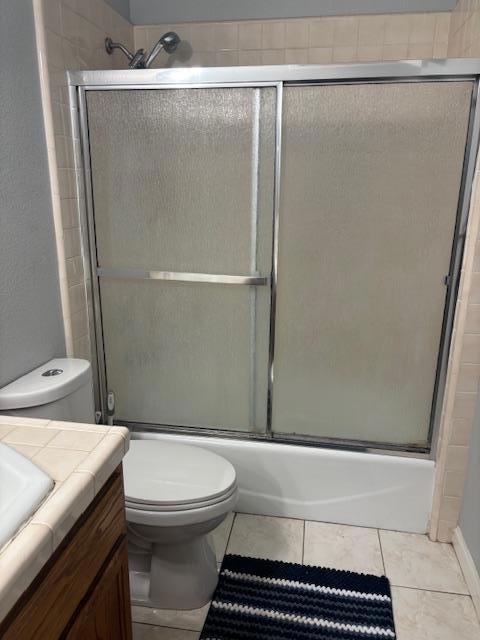 full bathroom with toilet, combined bath / shower with glass door, tile patterned floors, and vanity