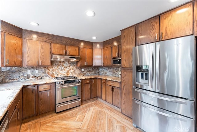 kitchen with light stone countertops, backsplash, stainless steel appliances, and light parquet floors