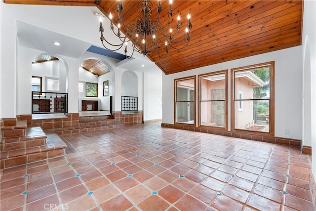 unfurnished living room with tile patterned flooring, high vaulted ceiling, wooden ceiling, and a notable chandelier