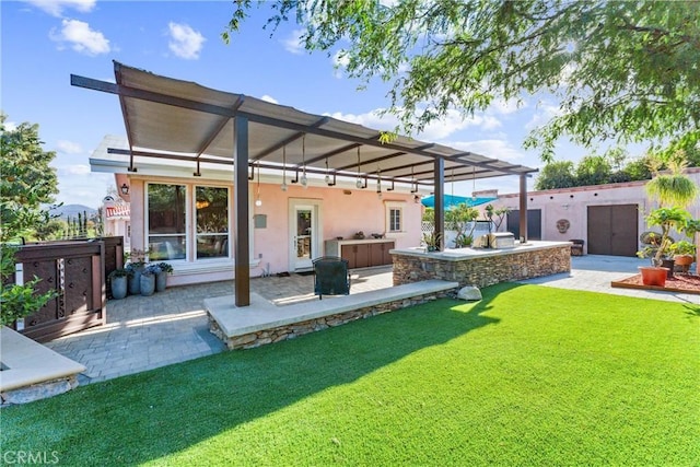 rear view of property with a yard, a patio, a pergola, and exterior kitchen