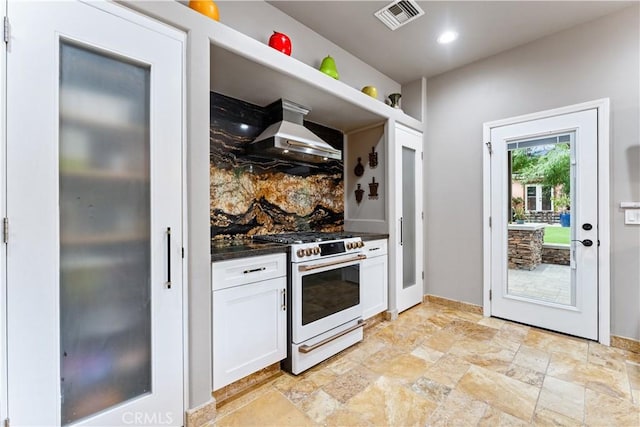 kitchen featuring tasteful backsplash, white cabinetry, white gas stove, and wall chimney exhaust hood