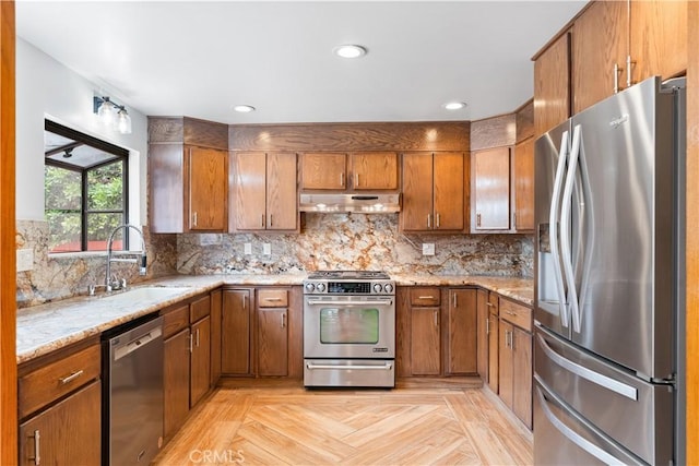 kitchen with light stone countertops, sink, stainless steel appliances, tasteful backsplash, and light parquet floors