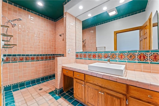 bathroom with tile patterned floors, vanity, tile walls, and tiled shower