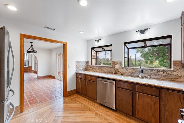 kitchen featuring appliances with stainless steel finishes, backsplash, light parquet floors, and sink