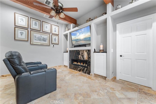 living room with a high end fireplace, built in features, and ceiling fan