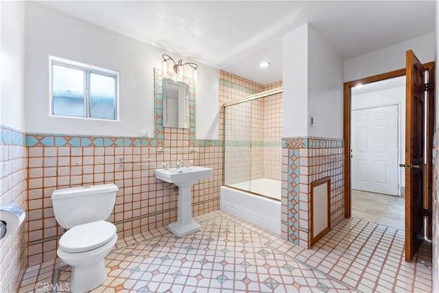 11431 Clybourn Ave, Lakeview Terrace, CA 91342 - full bath featuring tile walls, wainscoting, bath / shower combo with glass door, and toilet
