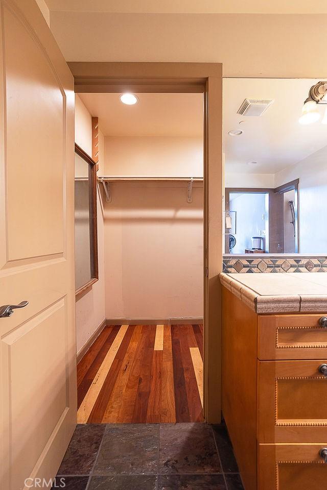 walk in closet with dark wood-type flooring