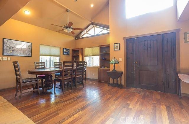 dining room featuring dark wood-type flooring, high vaulted ceiling, and ceiling fan