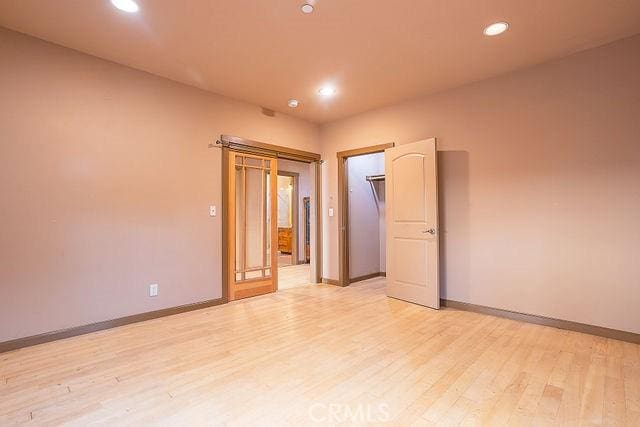empty room featuring recessed lighting, light wood finished floors, and baseboards